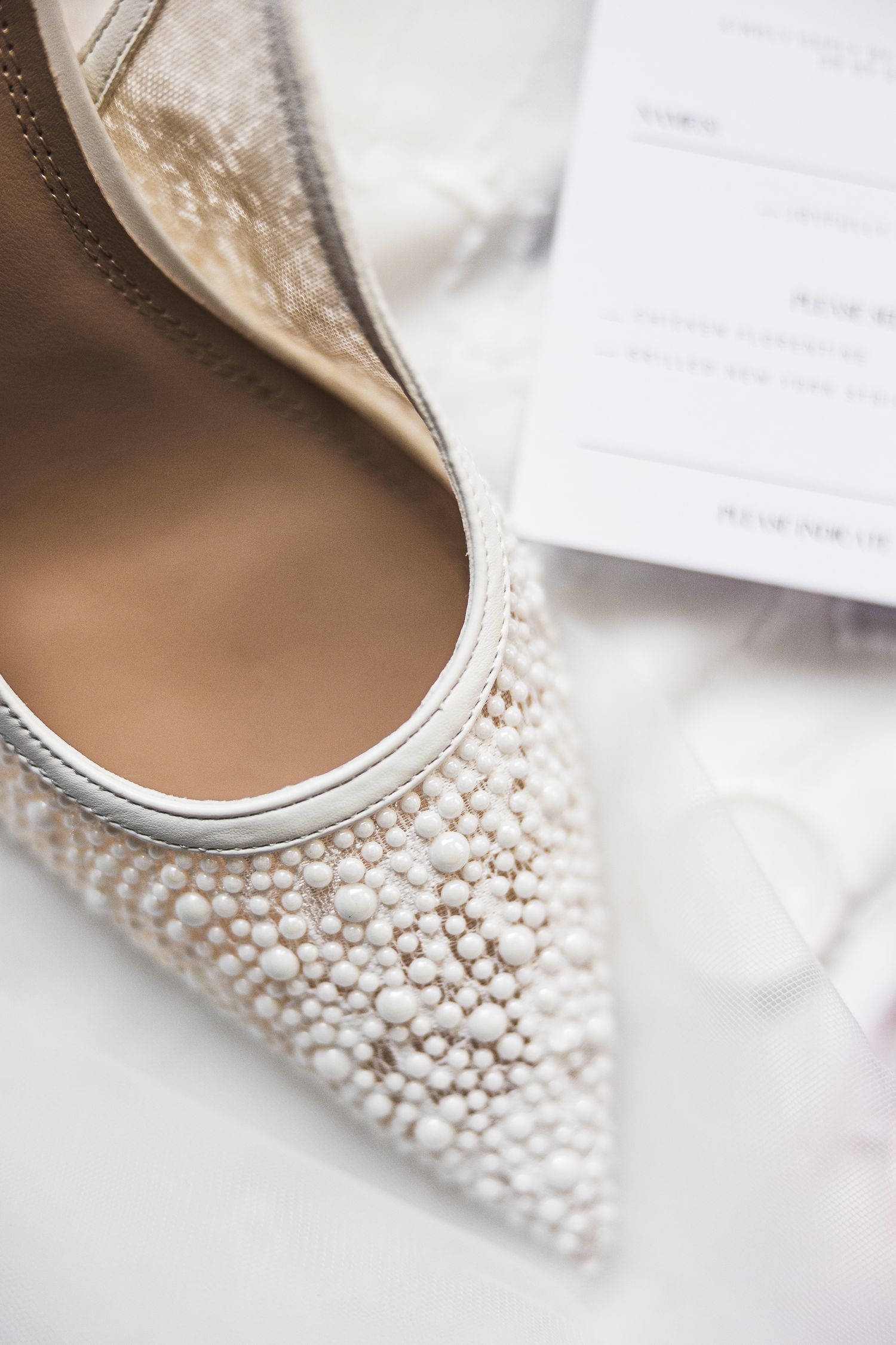 Elegant bridal shoe with pearl embellishments photographed on white background.