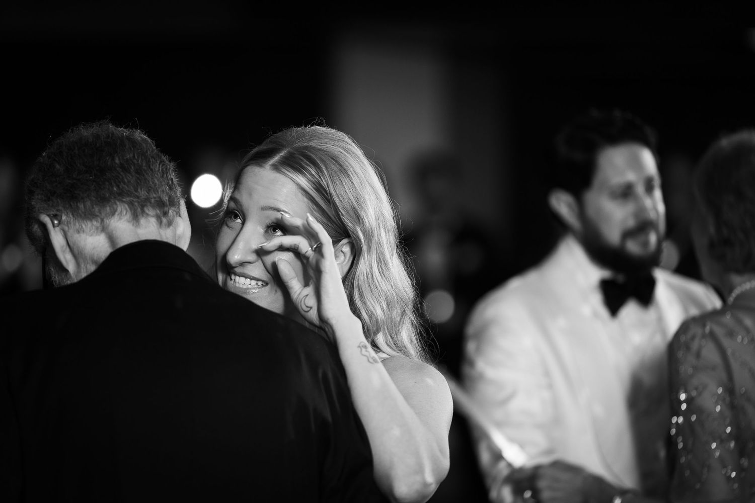 Black and white candid photo of people at a formal event with dancing and laughter.