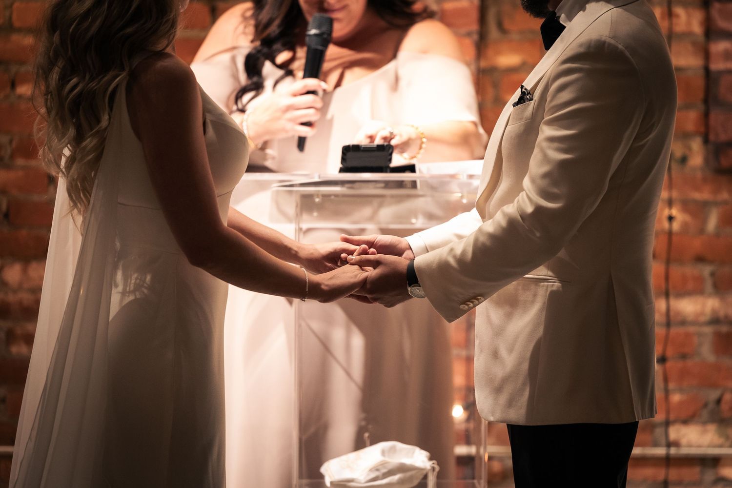 A romantic wedding couple dancing together in an intimate moment on a rustic brick-walled dance floor.