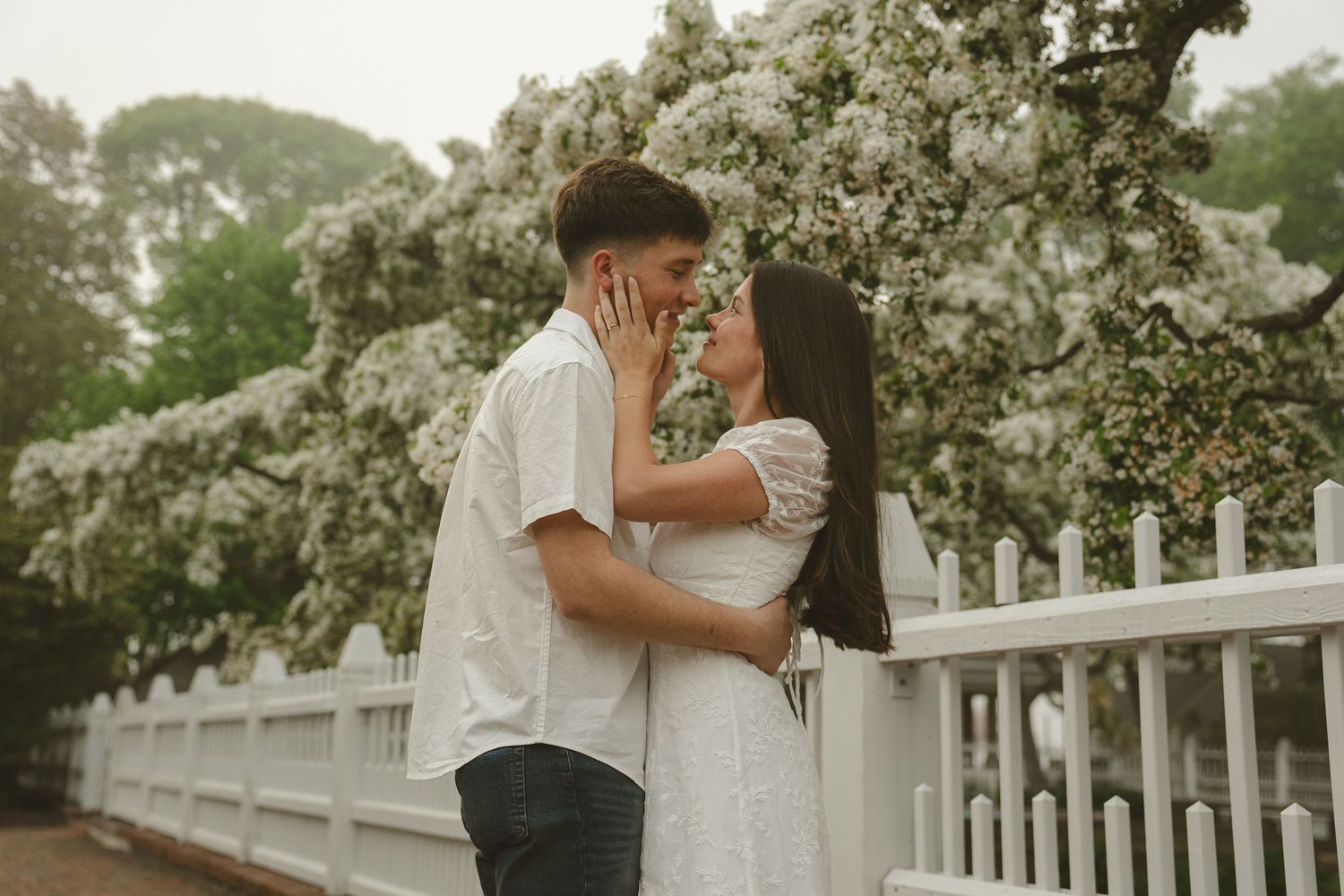 Bride and groom kissing their dog wearing a blue bow tie with floral garland.
