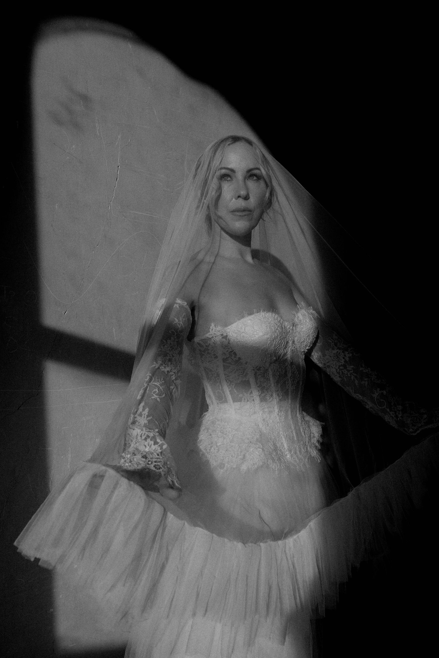 Artistic black and white fashion portrait series showing ethereal movement of a flowing white dress against dark background.