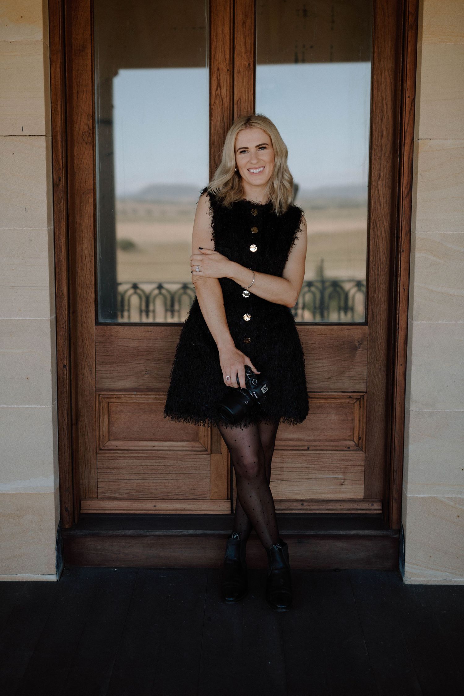 A series of four photos showing someone in a black dress sitting on wooden steps in front of rustic doors.