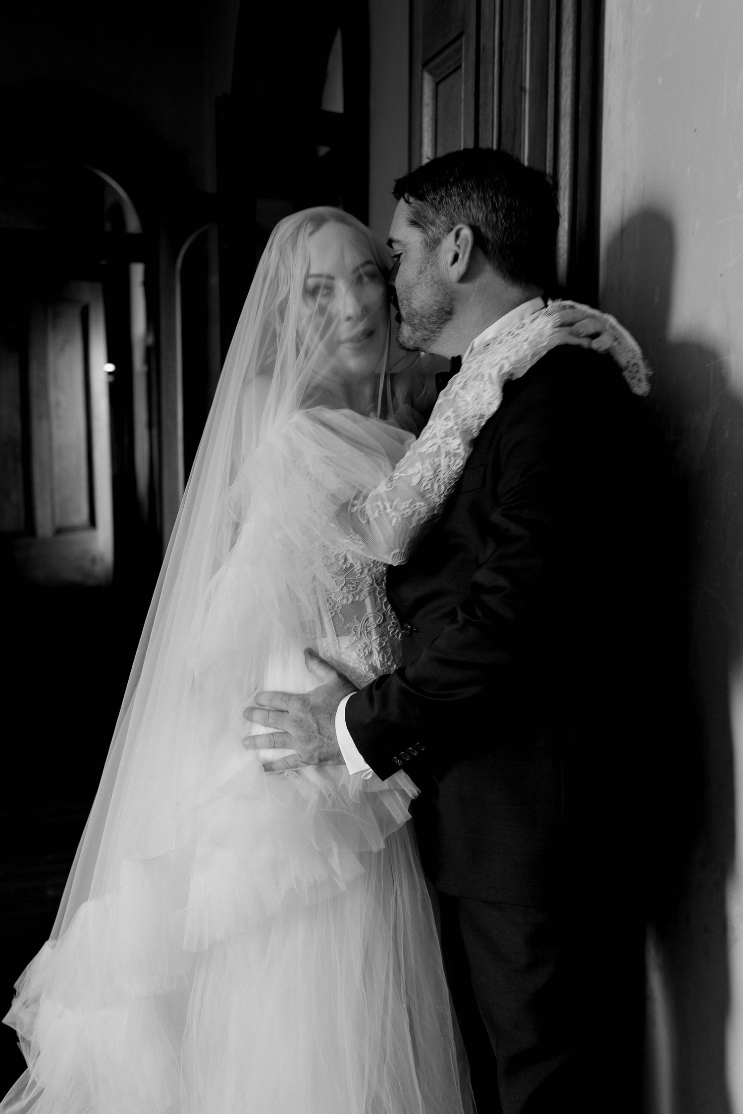A romantic black and white photo series of newlyweds sharing their first kiss at a wedding ceremony.
