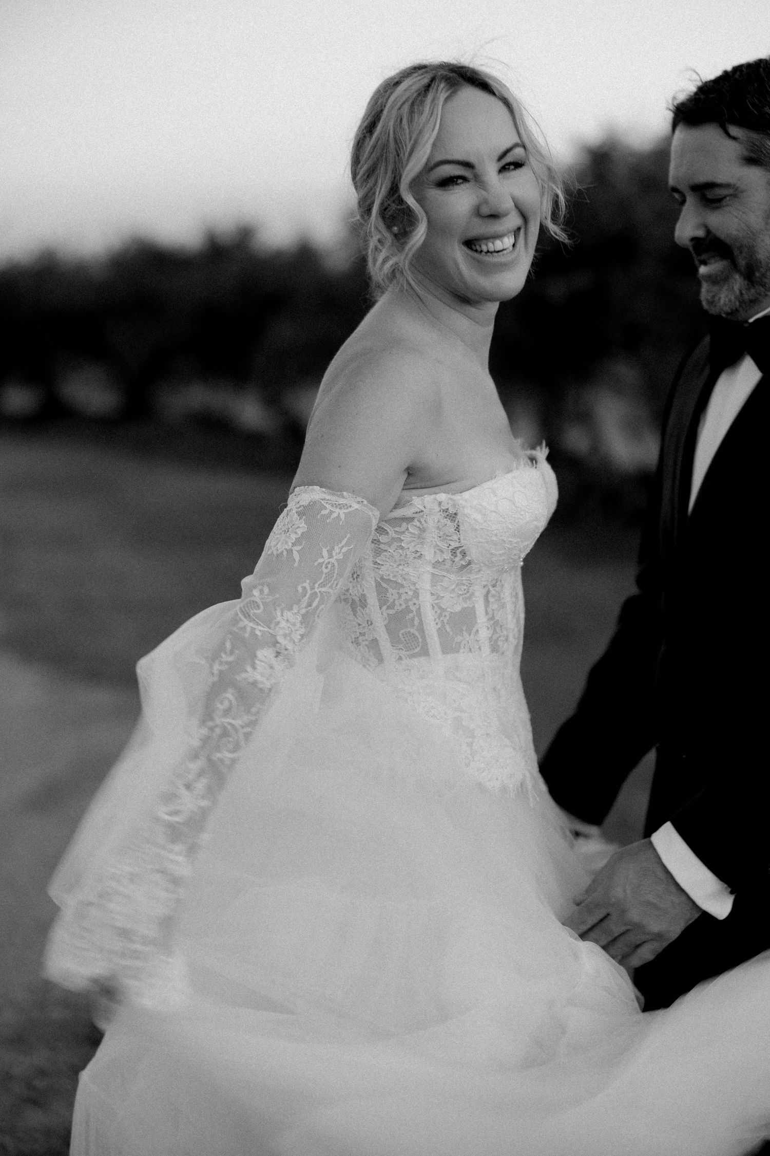 A romantic black and white wedding photo series showing joyful moments between a couple in formal attire outdoors.
