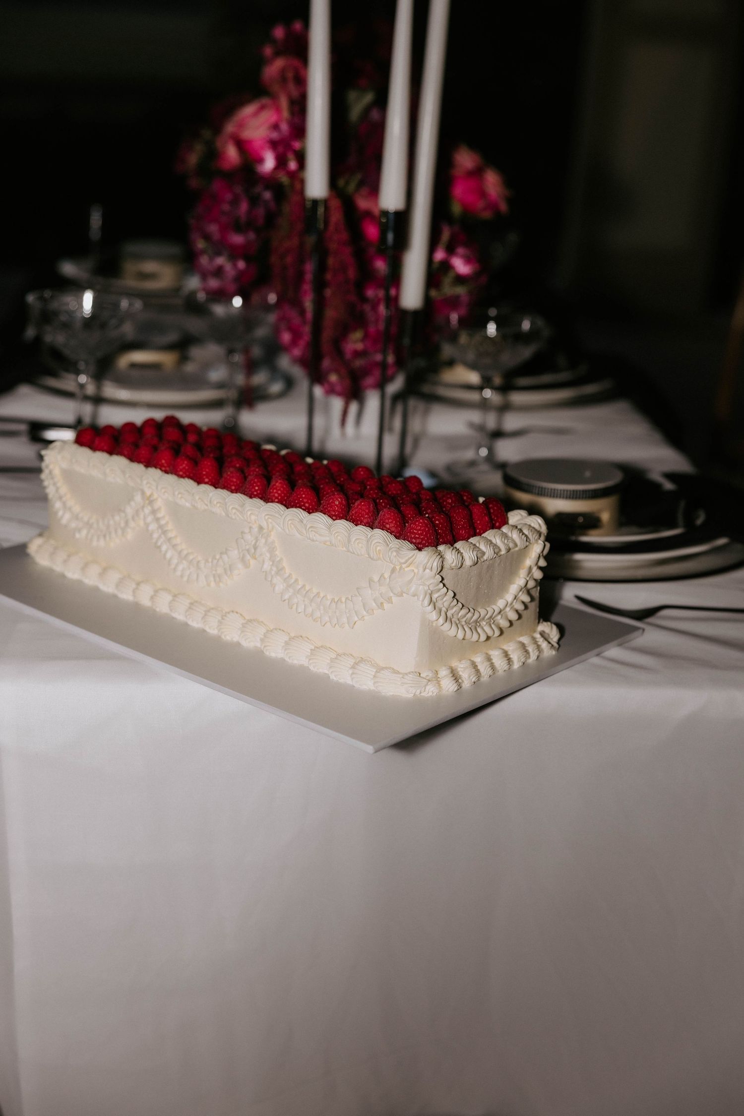 A white high heel shoe decorated with pearls and red roses sits elegantly on a table at a formal event.