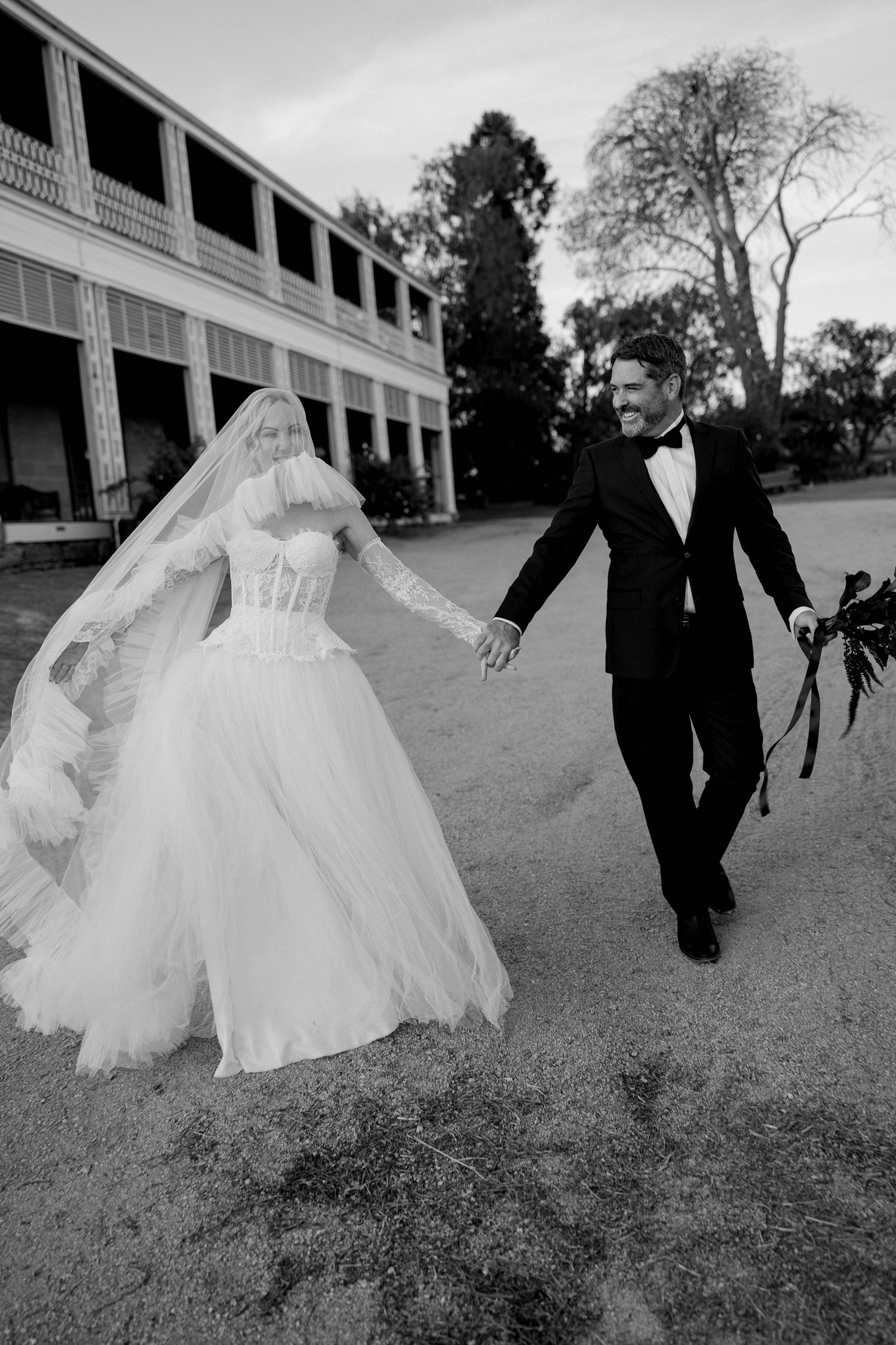 A sequence of black and white photos showing a bride and groom playfully running across a grassy lawn.