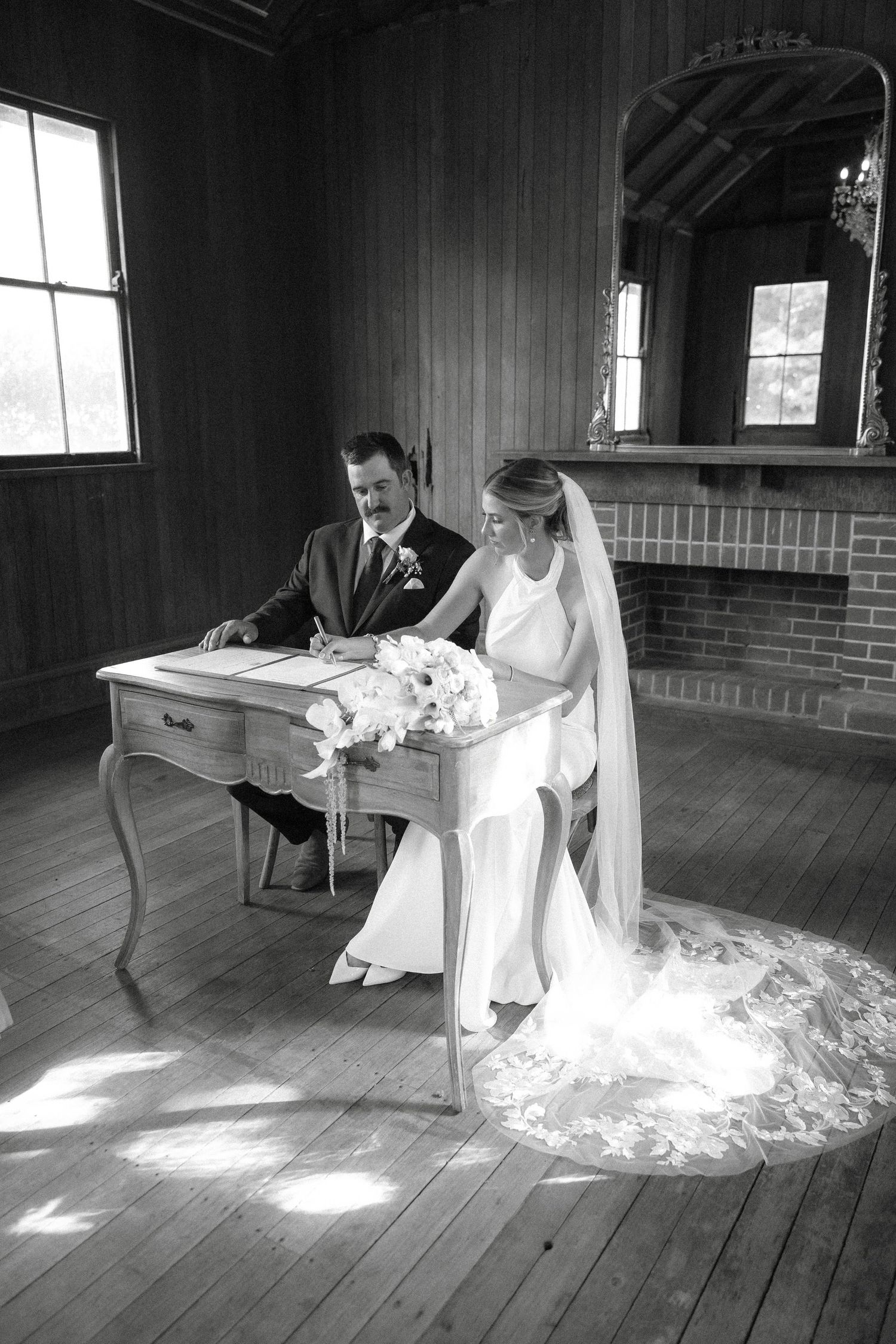 A series of black and white wedding photos showing a couple signing documents in an elegant  indoor setting. Gabbinbar homestead Toowoomba