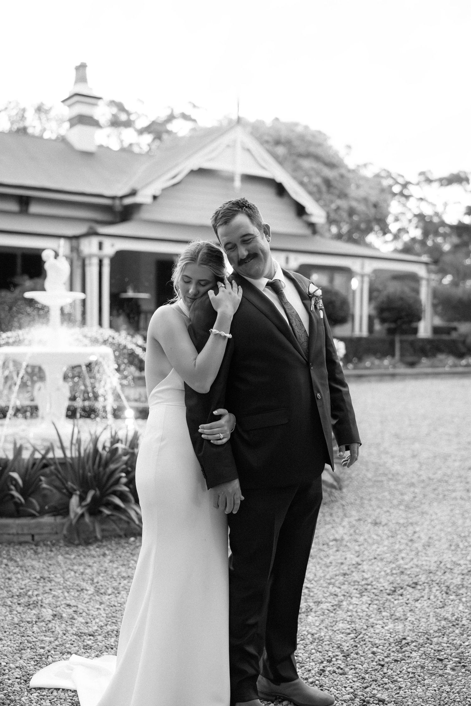 Black and white wedding photos show intimate moments between couple embracing outdoors on gravel path. Gabbinbar Homestead toowoomba