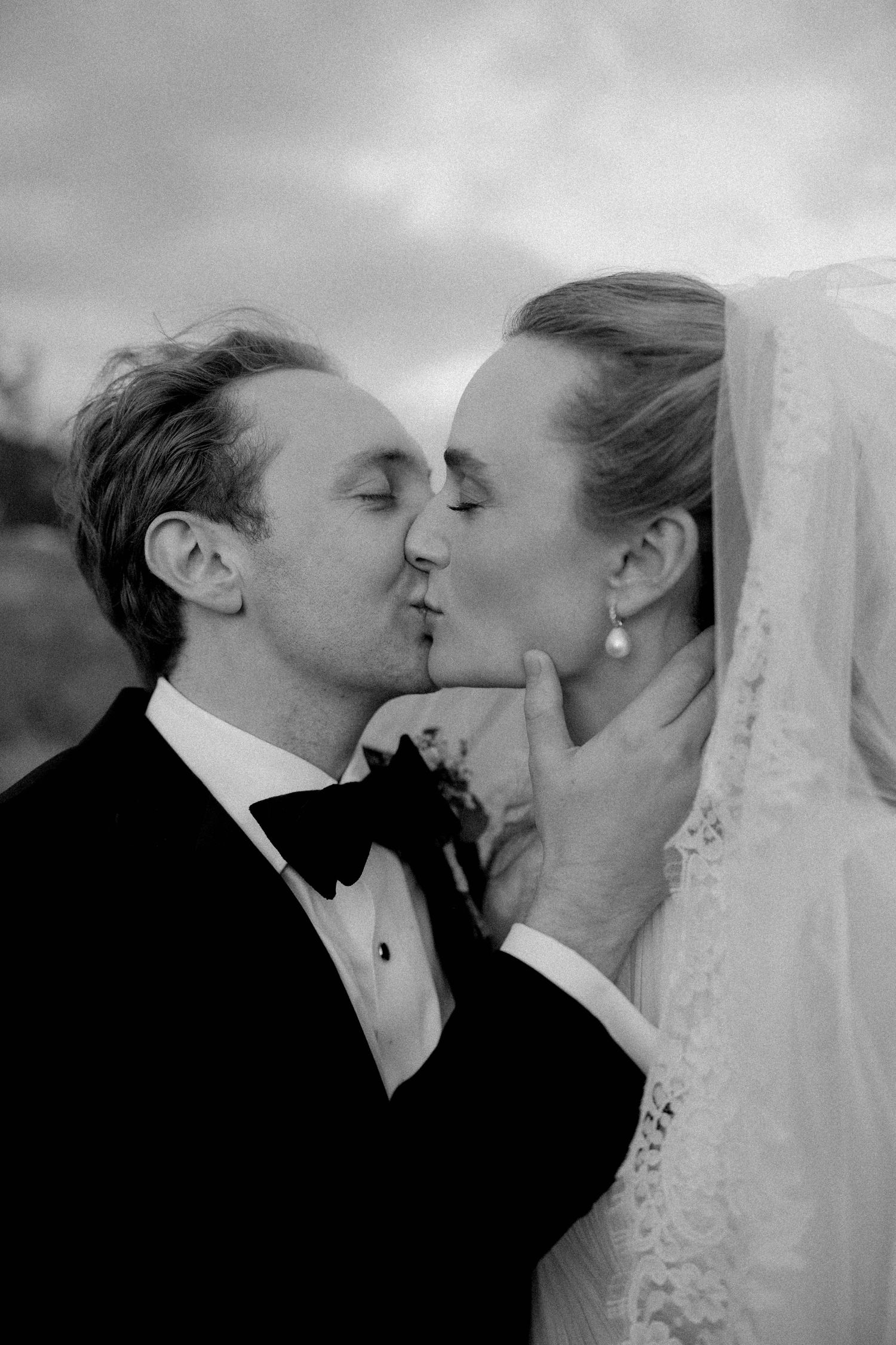 Black and white photo of a bride and groom sharing a romantic kiss on their wedding day.