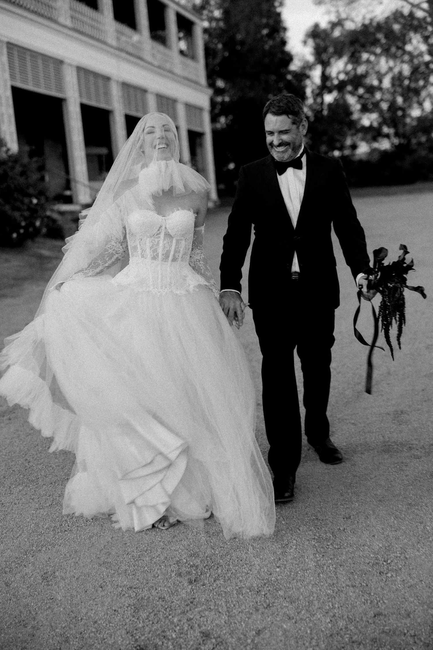 Black and white wedding photos showing couple walking together with bride's dress flowing in a romantic outdoor setting.