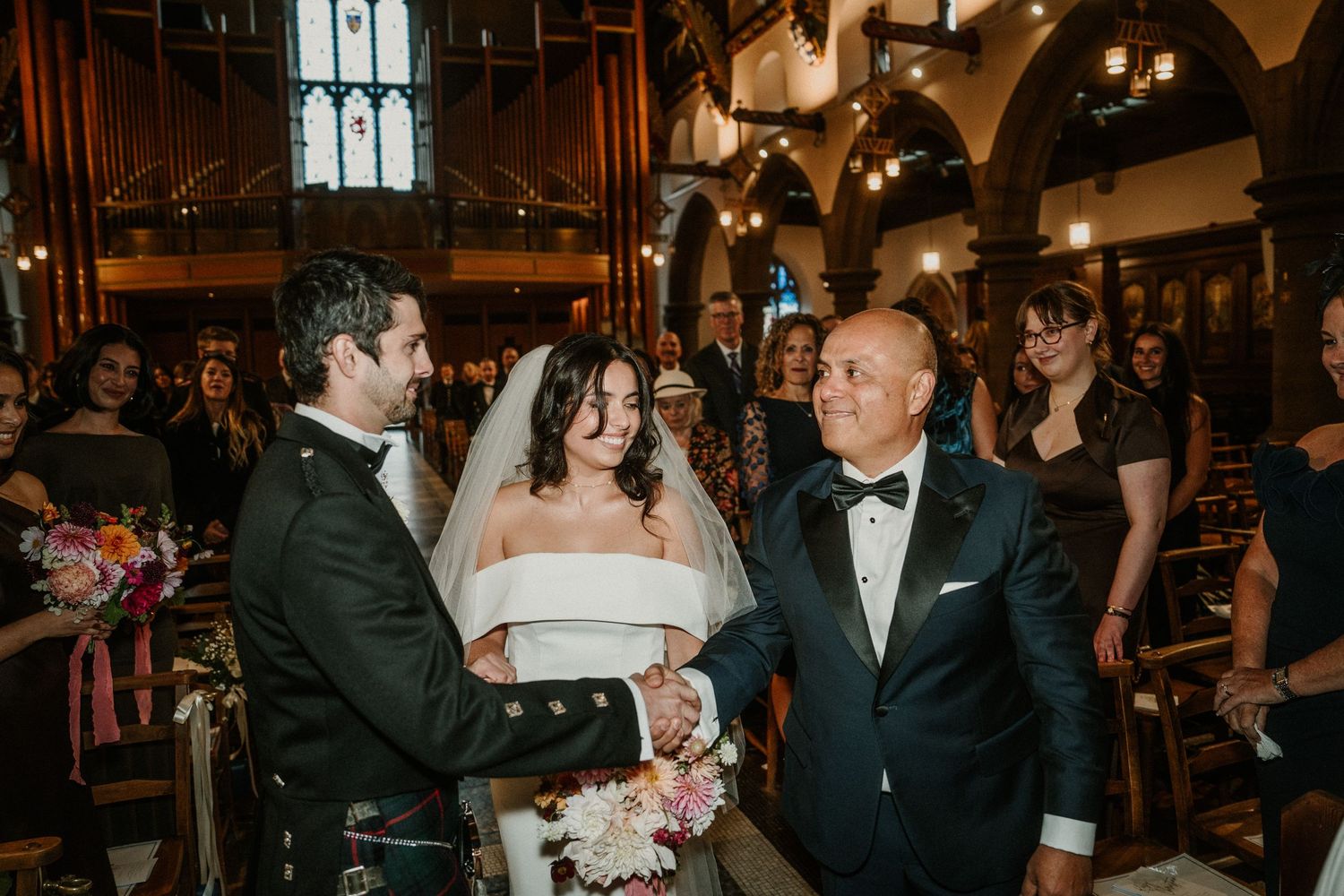 Wedding ceremony moment inside historic church with gothic architecture and stained glass windows.