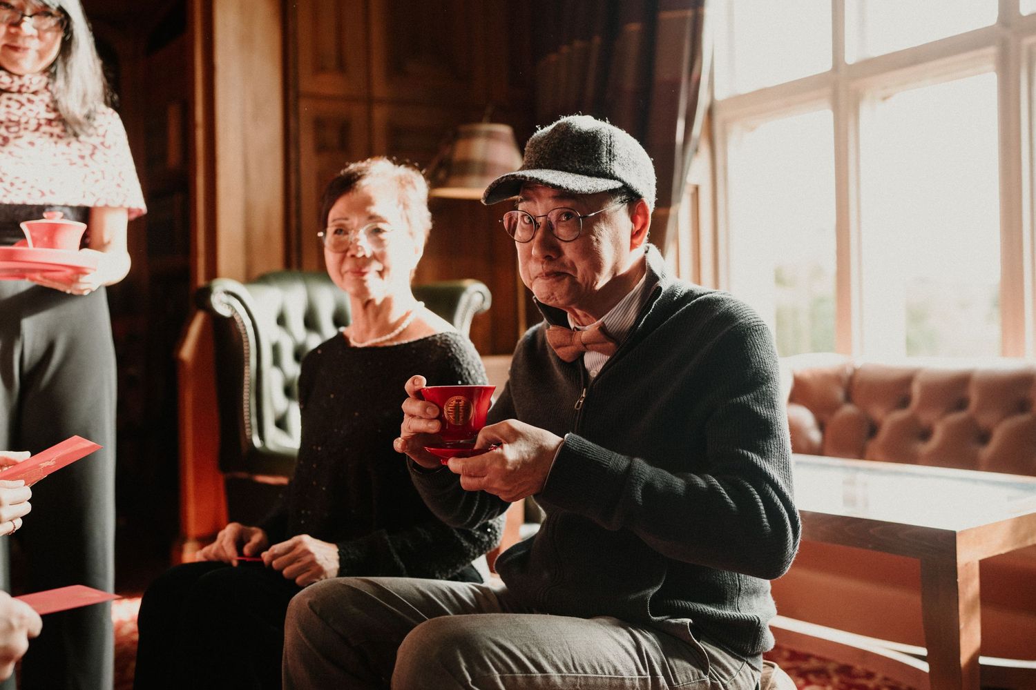 Wedding guests enjoying drinks and conversation in an elegant venue with natural lighting.