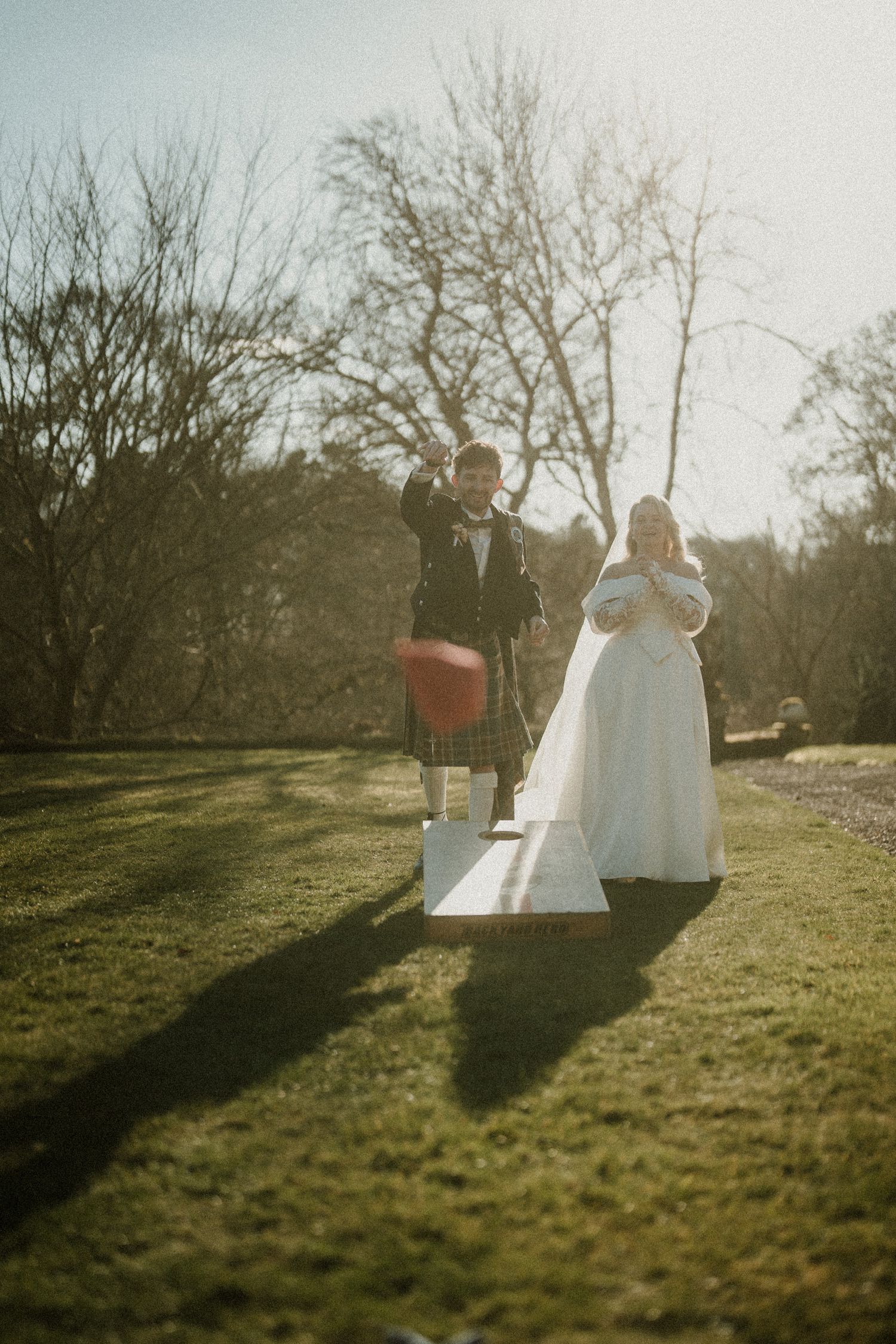 Sunlit silhouette of Scottish wedding couple standing on outdoor pathway.