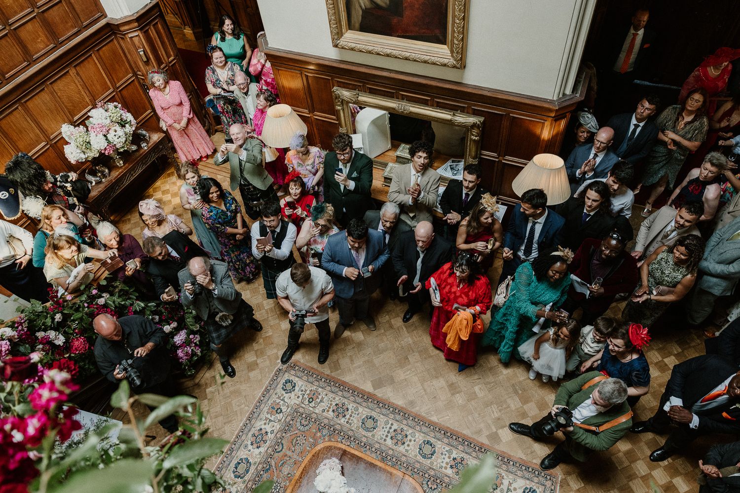 Overhead view of wedding reception with guests seated at decorated tables in grand hall.