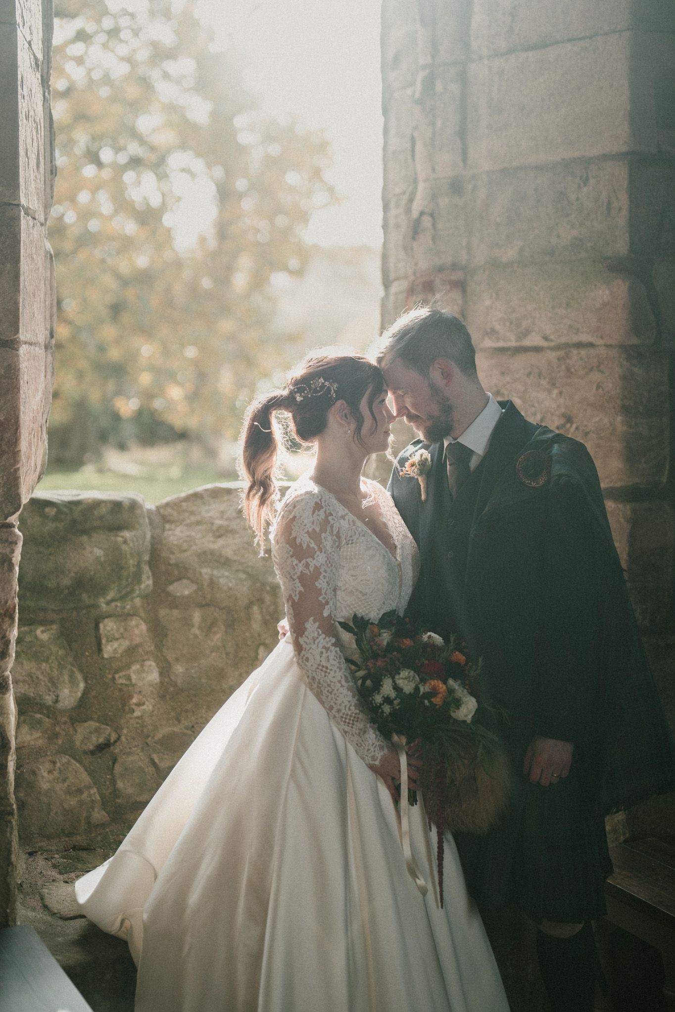 Romantic wedding portraits captured in stone archway with natural lighting.