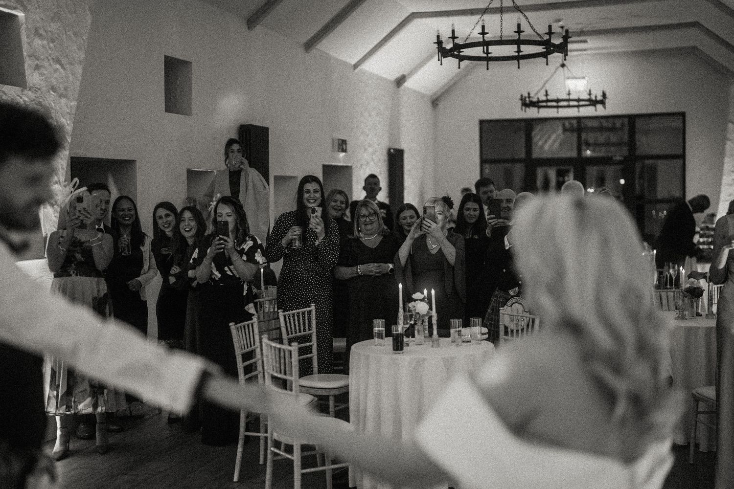 Black and white photo of wedding reception dance floor with guests in motion.