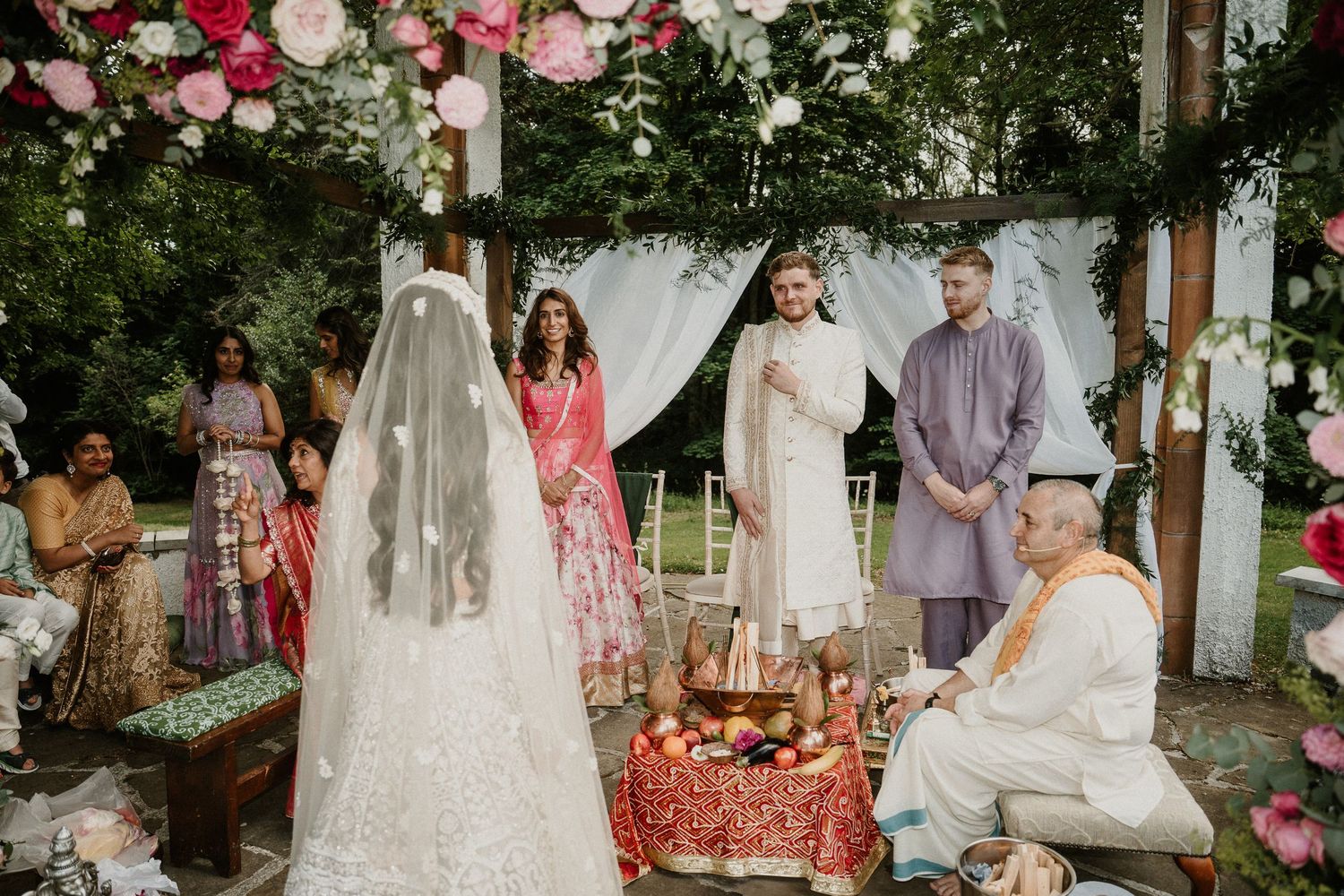 Garden wedding ceremony with floral arch and white chairs set up on manicured lawn.