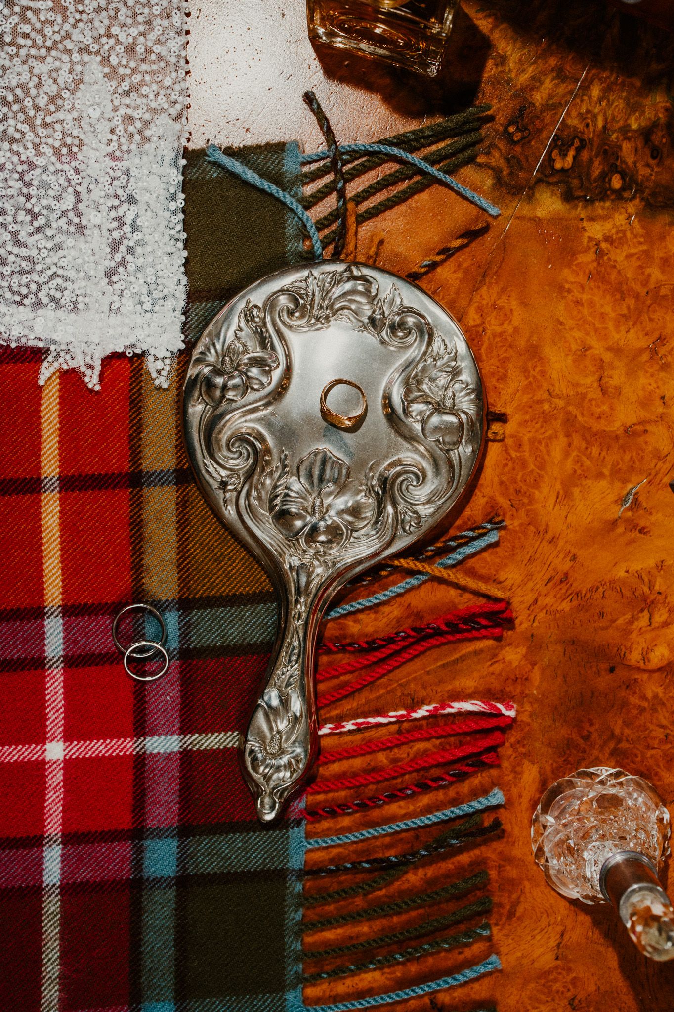 Ornate silver accessories and wedding rings arranged on plaid tartan fabric.