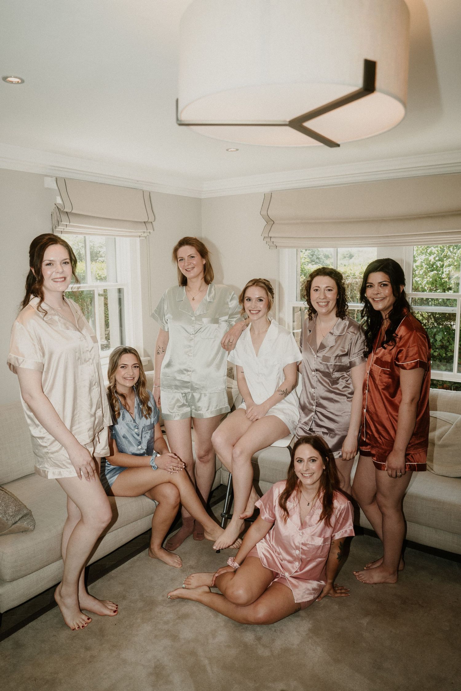 Group wearing matching silk robes and pajamas pose together during pre-wedding preparations.