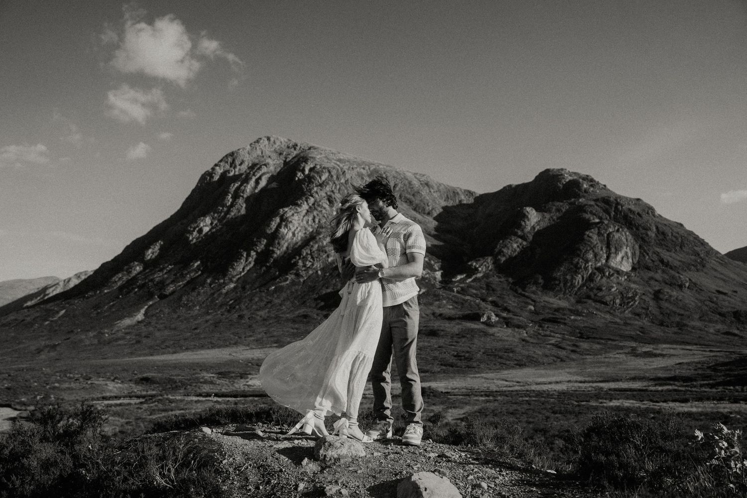 Black and white landscape photo of couple embracing in Scottish highlands.