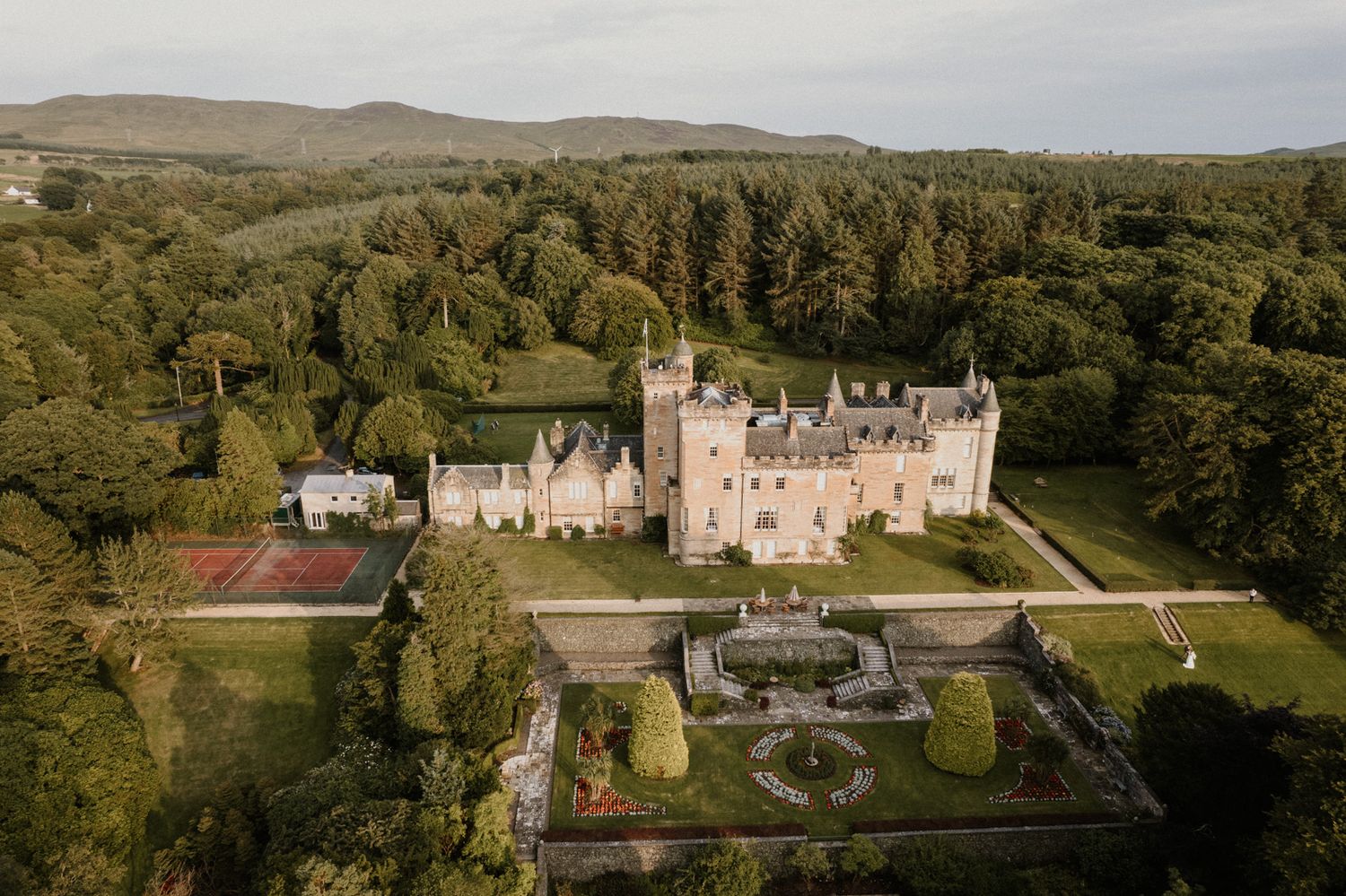 Panoramic view of a Scottish castle estate surrounded by rolling hills and greenery.
