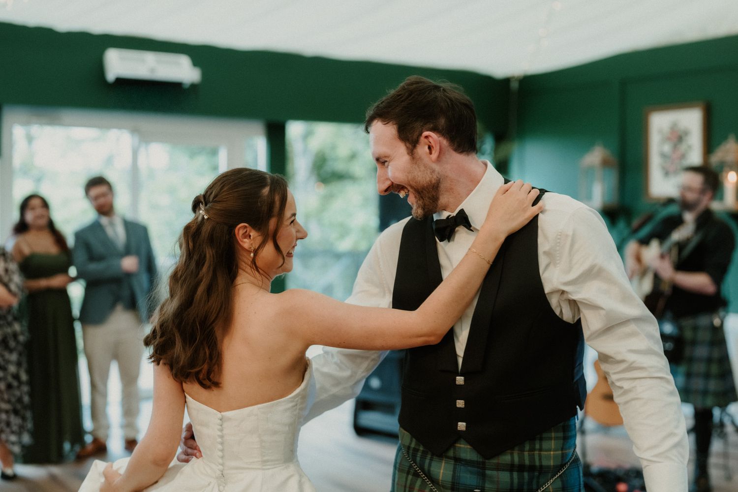 Bride and groom sharing first dance, groom wearing traditional Scottish tartan kilt.