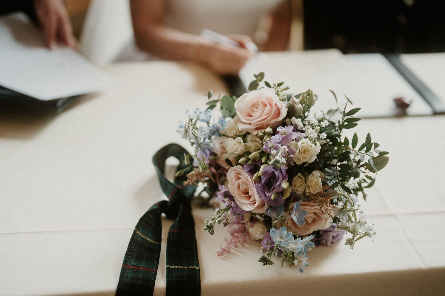 Close-up of delicate pastel wedding bouquet with roses and mixed flowers.