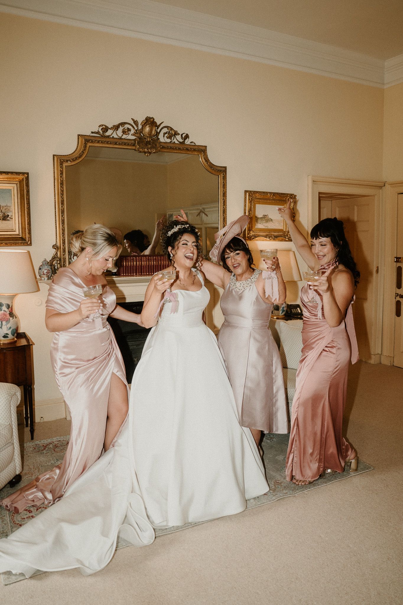Bridal party in matching pink dresses performs a synchronized falling pose with the bride.