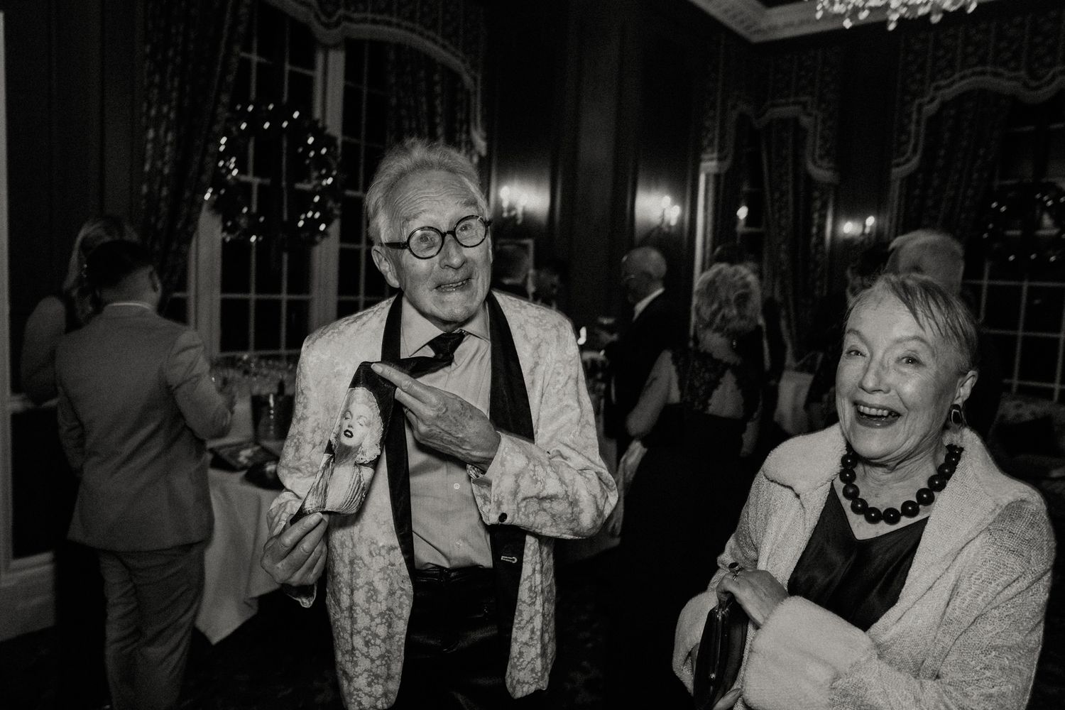 Wedding guests dance and celebrate in a dimly lit reception venue.
