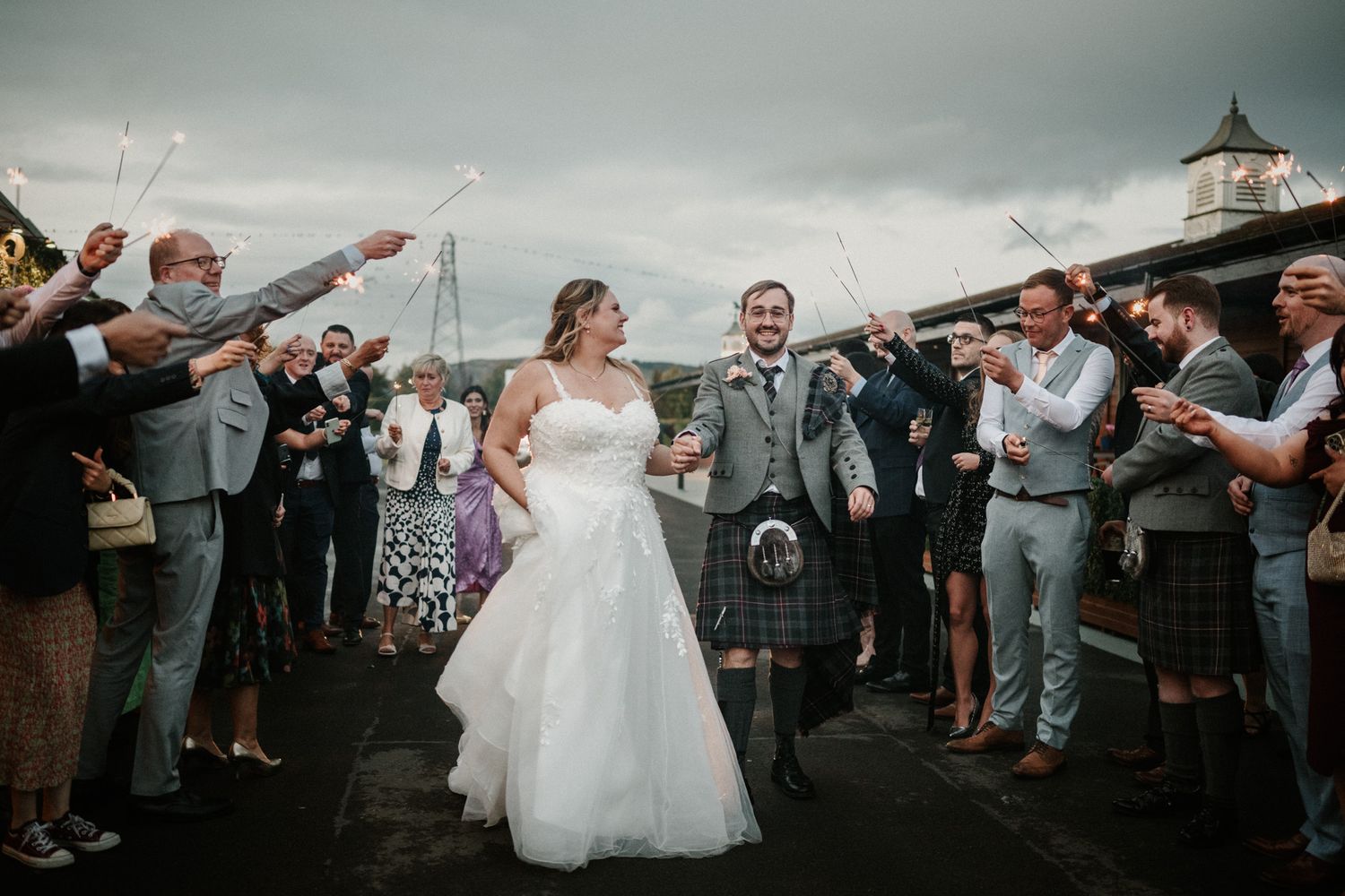 Wedding party walks through a shower of confetti during outdoor celebration.
