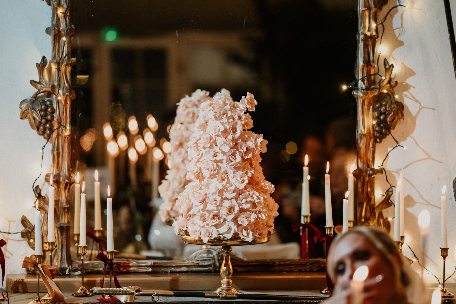 Long banquet table with romantic candlelight and floral decorations in an elegant indoor setting.