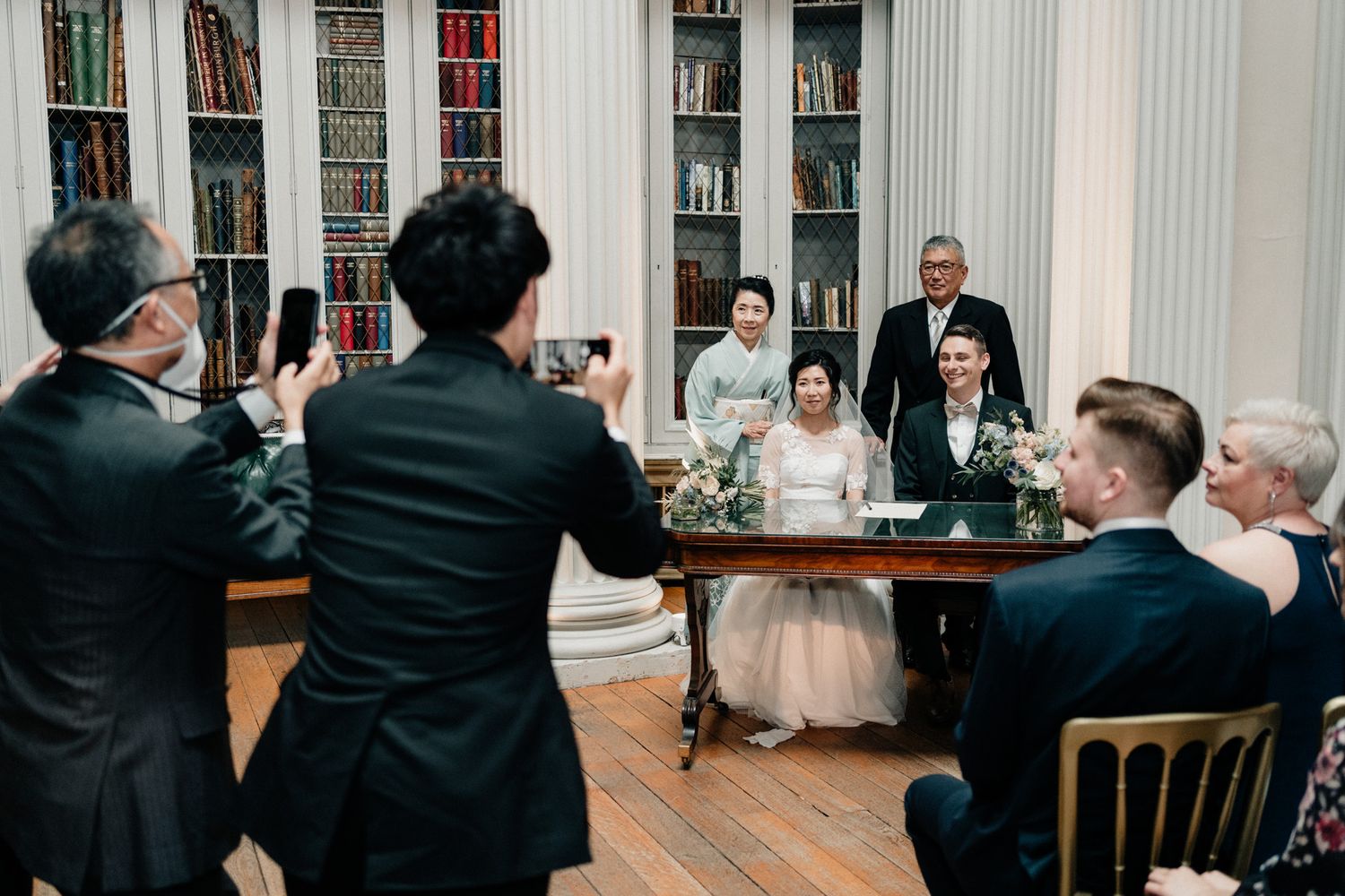 Wedding guests seated in rows during ceremony in classical architectural setting.