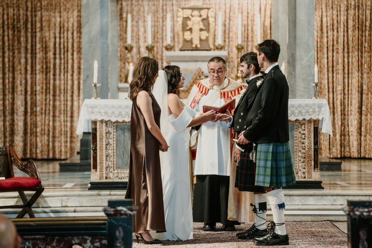 Traditional Scottish wedding ceremony taking place at ornate church altar with kilted attire.