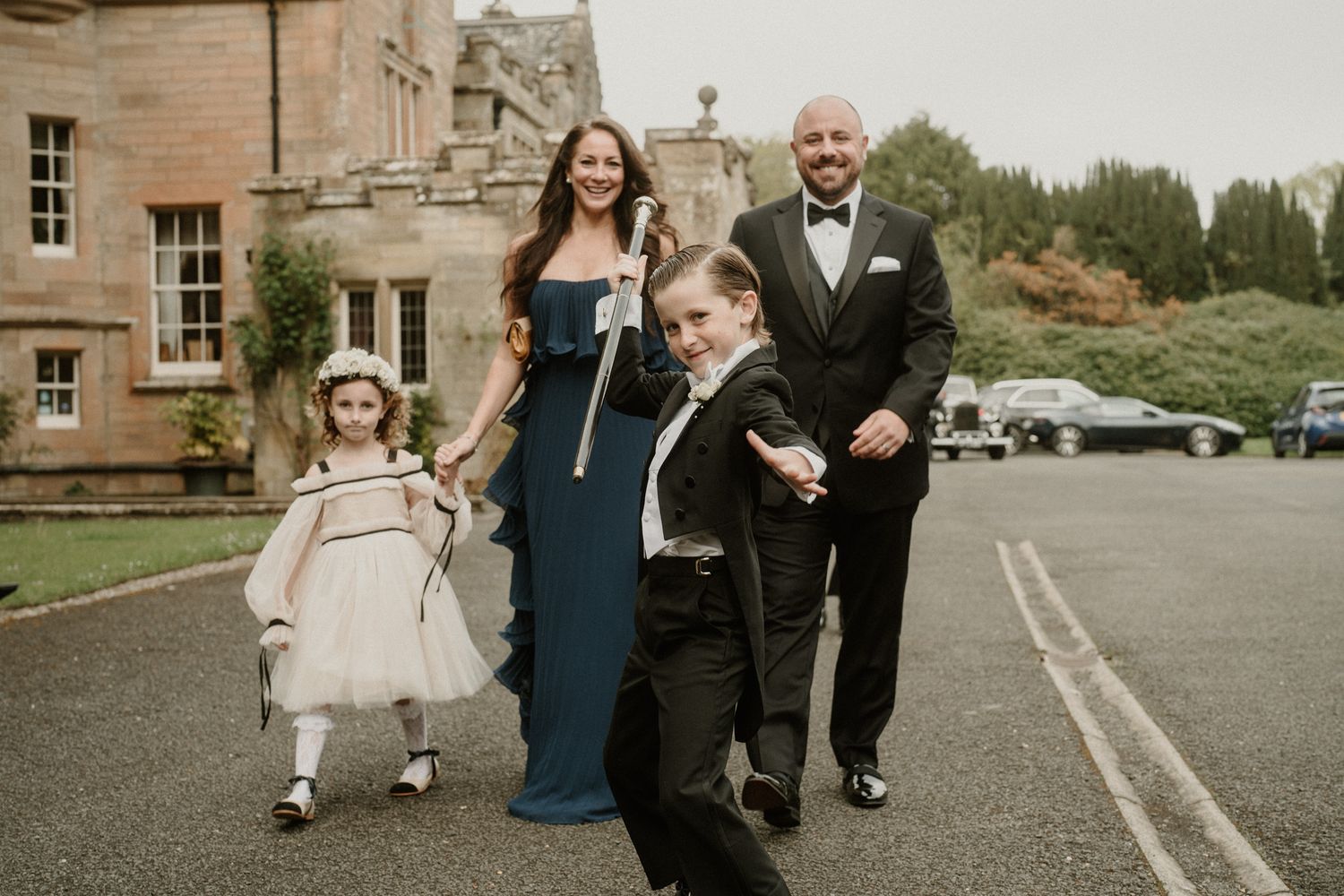 Wedding party members walking and laughing together on stone pathway.