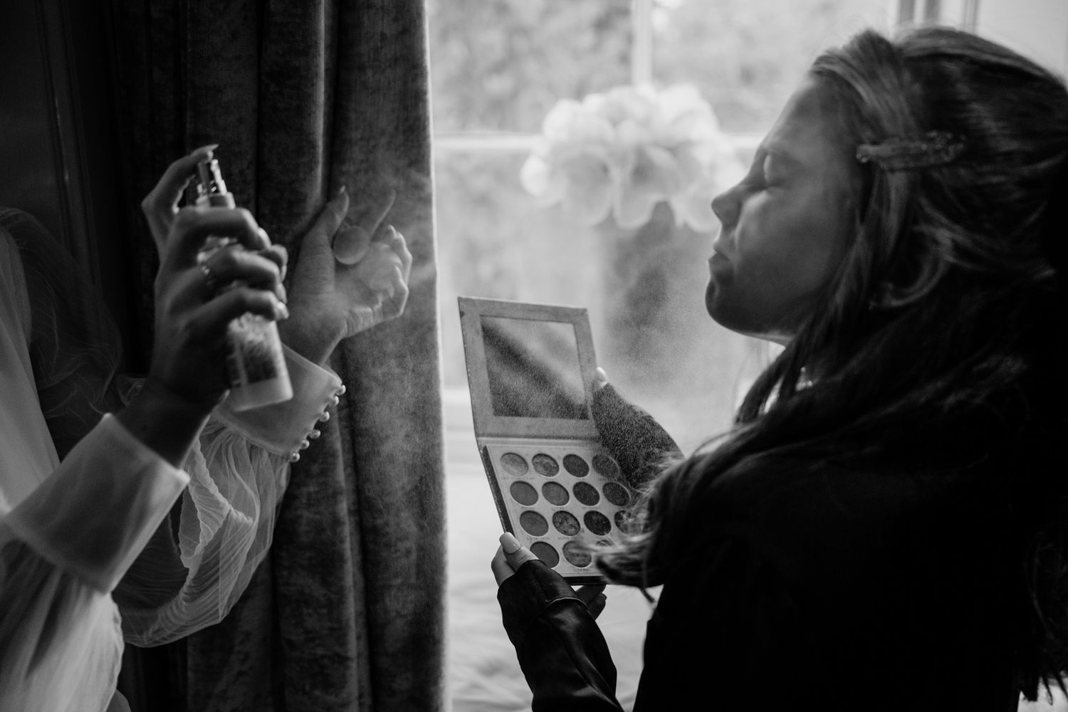 Black and white image capturing pre-wedding moments in a dimly lit room.