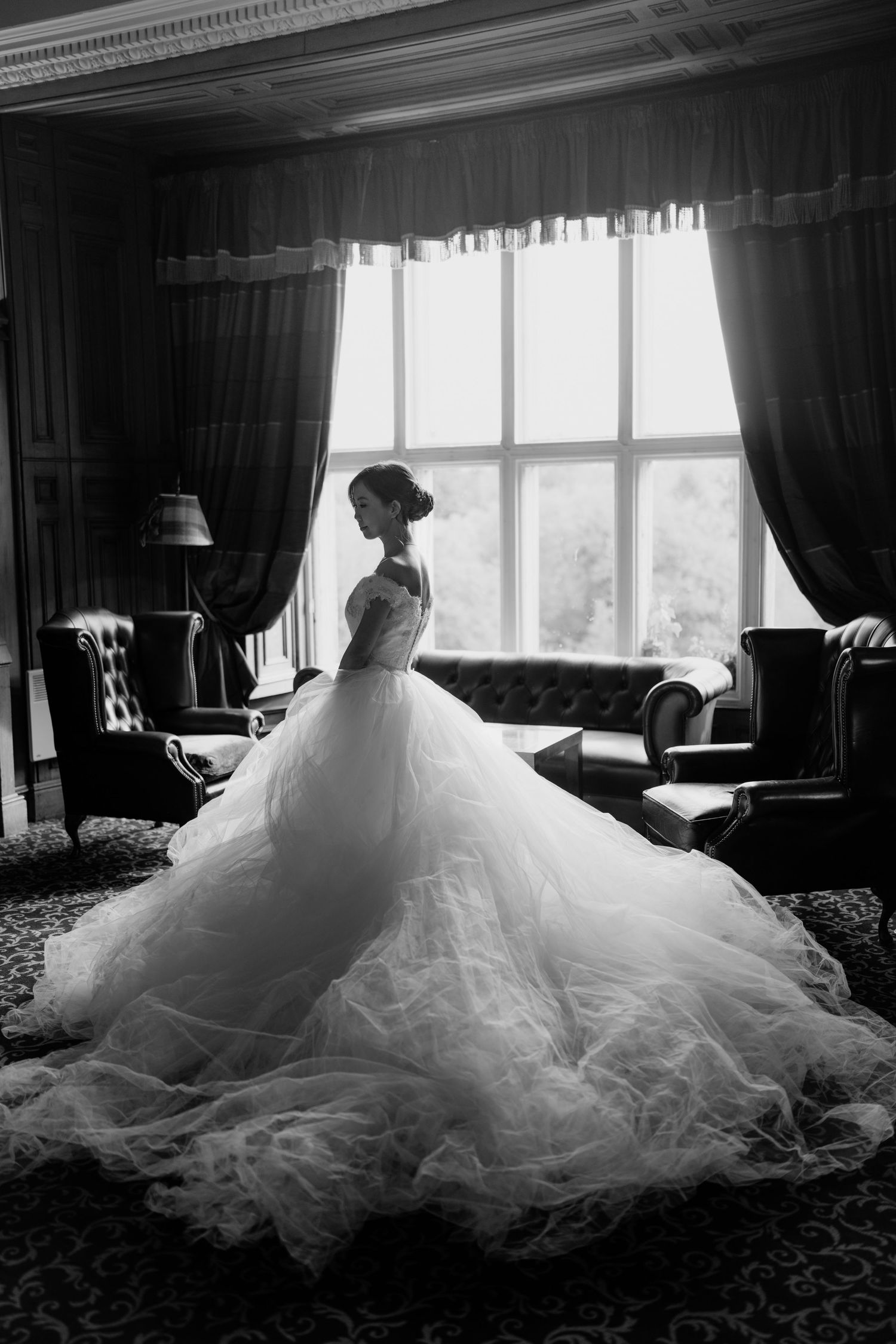 Dramatic black and white silhouette of a flowing wedding dress against window light.