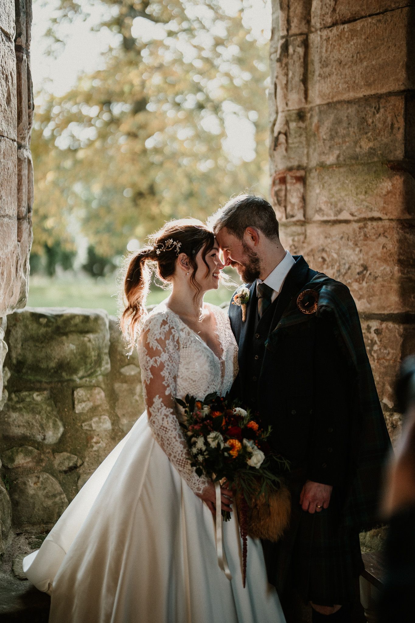 Romantic wedding portraits taken in historic stone archway with soft natural light.