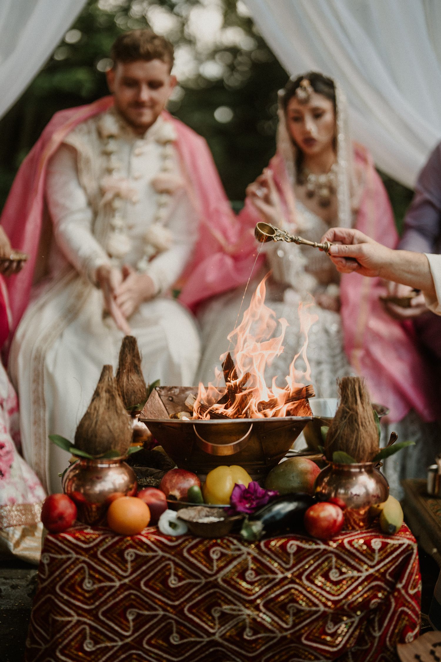 Traditional wedding ceremony with ornate decorations and ritual fire setup on patterned tablecloth.