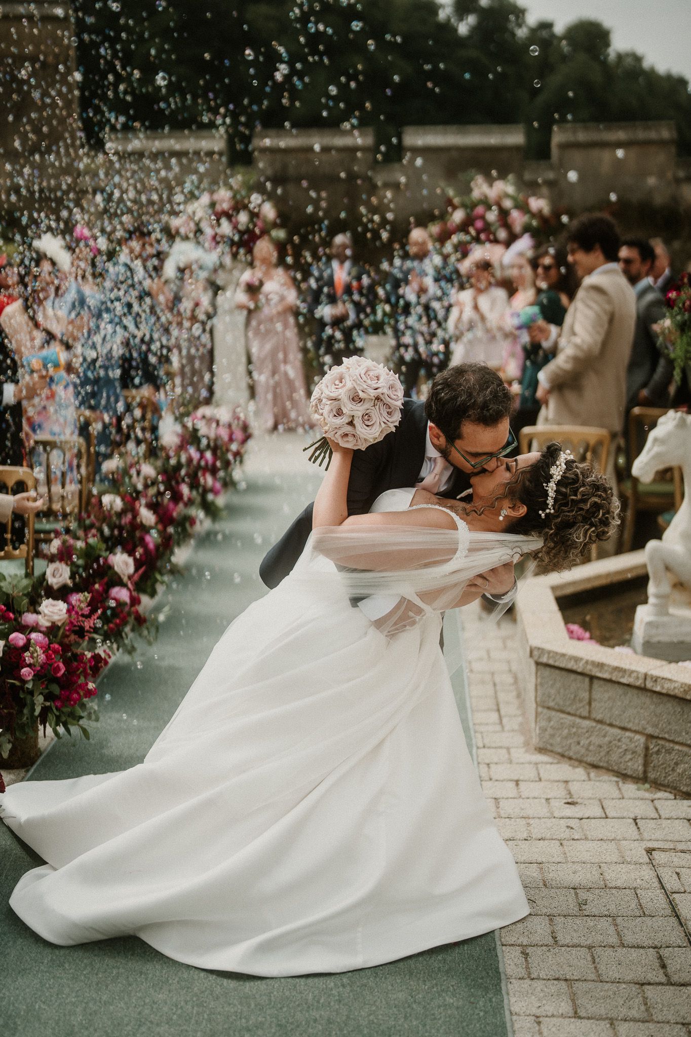 Romantic wedding dance moment surrounded by floating confetti and floral decorations.