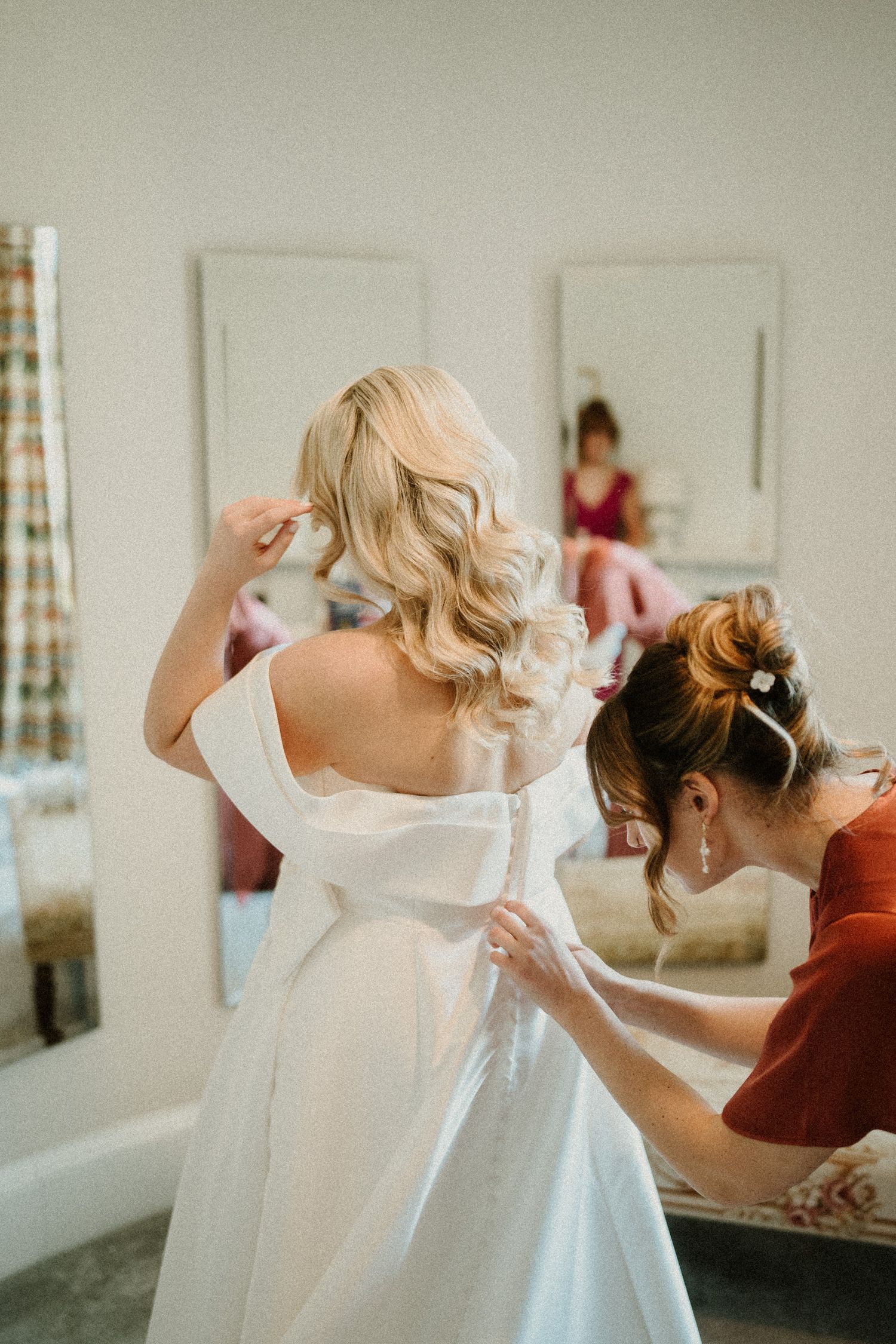 Wedding dress preparation scene showing final adjustments being made to a white gown.