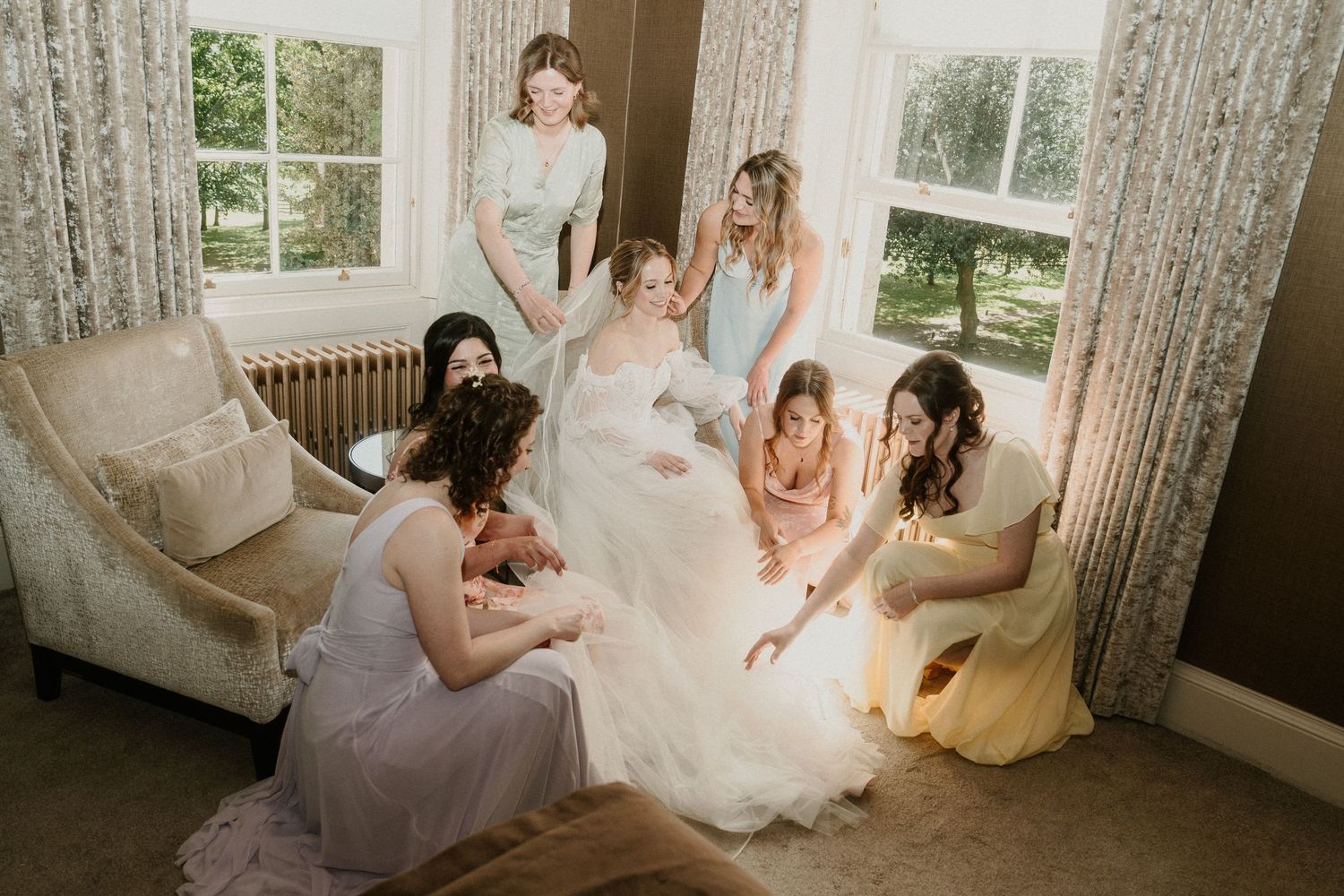 Candid moment of wedding party relaxing in elegant room with natural light.