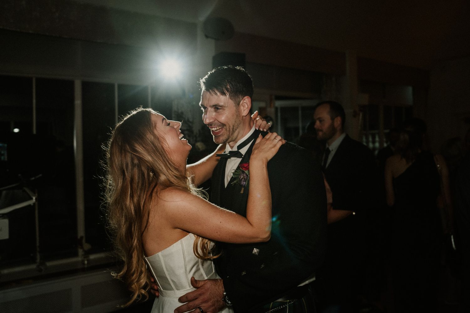 Dark moody reception venue with dramatic spotlighting and dancing silhouettes.
