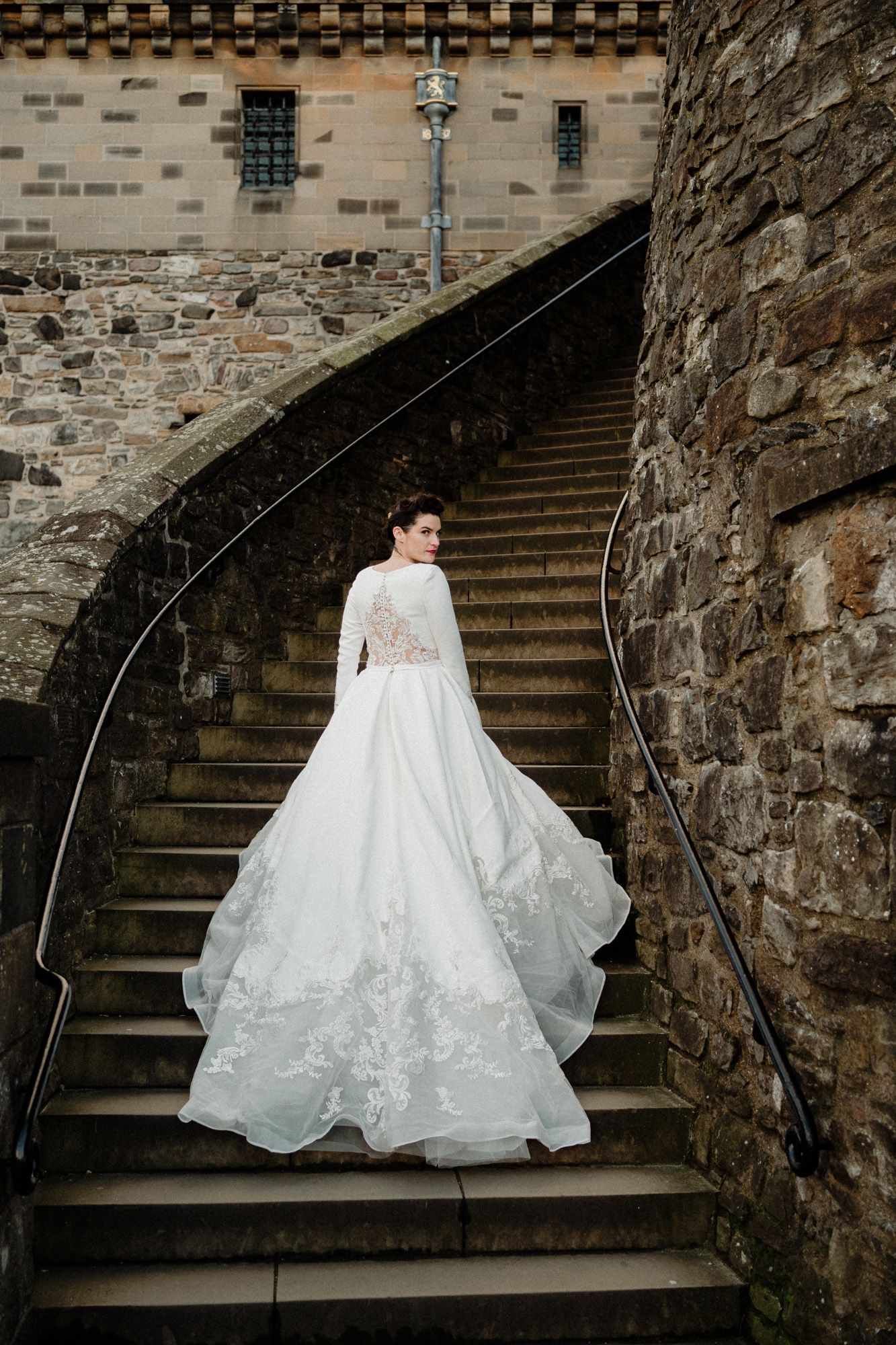 Elegant white wedding gown with lace details photographed on historic stone steps.