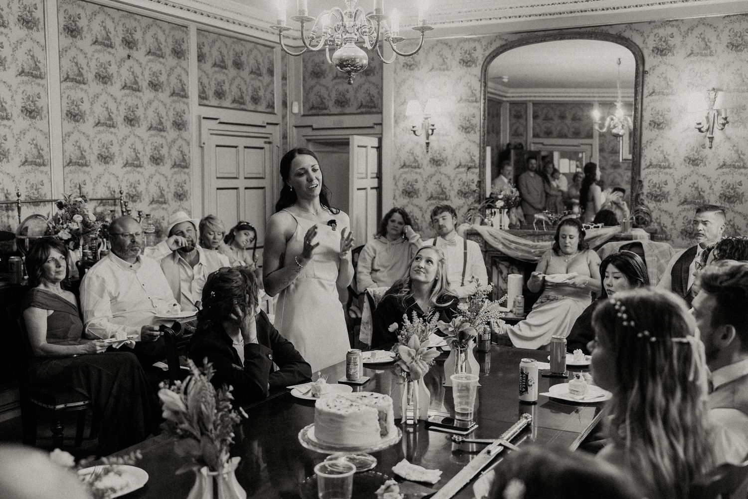 Black and white photo of a wedding guest giving a heartfelt speech at an elegant indoor reception.
