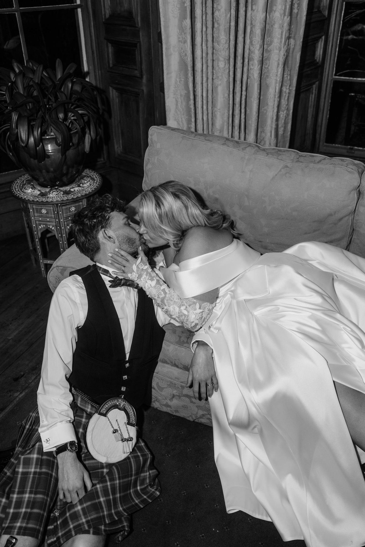 Black and white wedding photos of a couple in formal attire relaxing on a sofa.