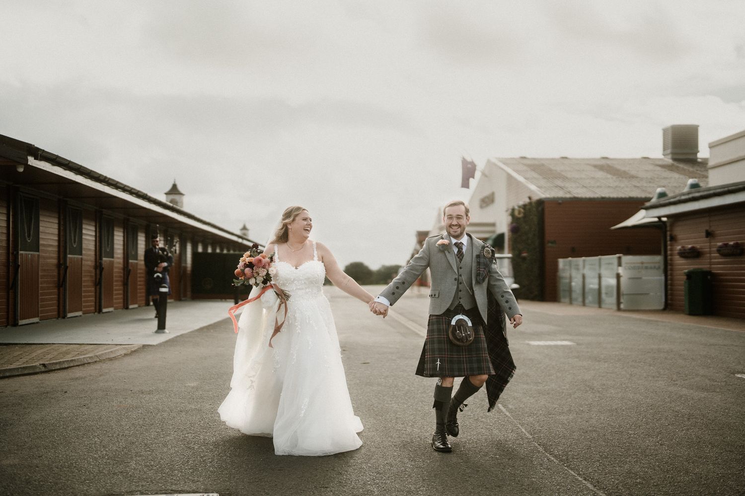 Panoramic view of a wedding couple posing outside industrial buildings.