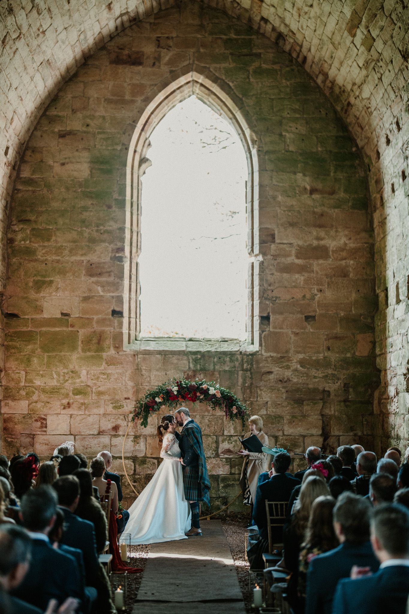 Intimate wedding ceremony in a historic stone chapel with gothic architecture and natural lighting.