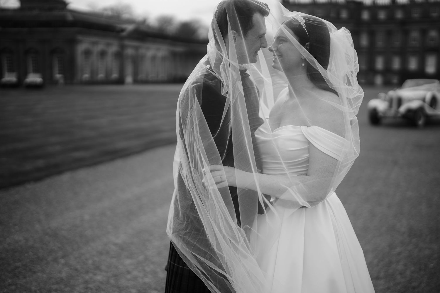 Ethereal bridal portrait with flowing veil against historic architecture.