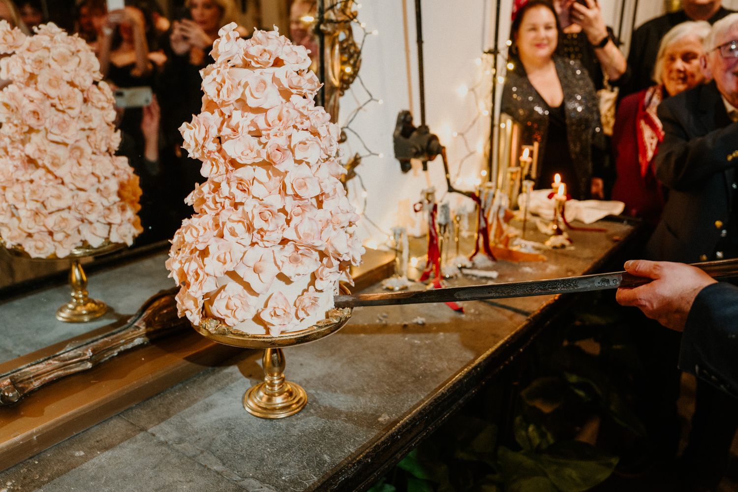 Elegant wedding cake display with gold candelabras and floral decorations.