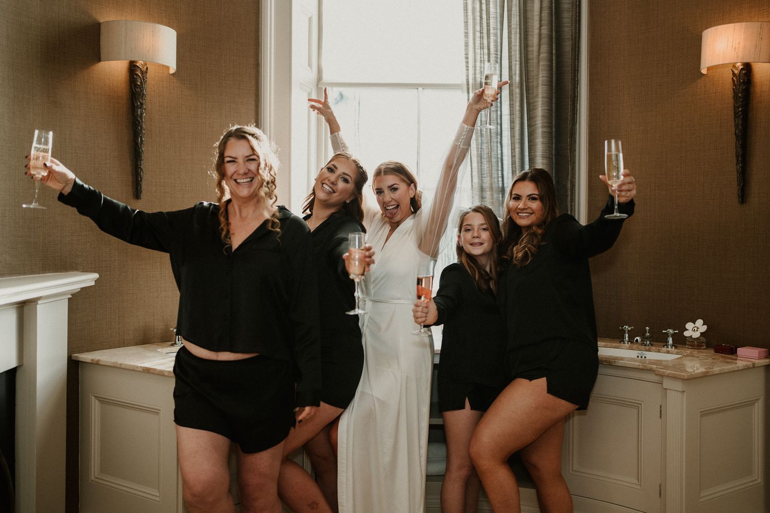 Wedding party celebrates in a elegant room with white walls and warm lighting.
